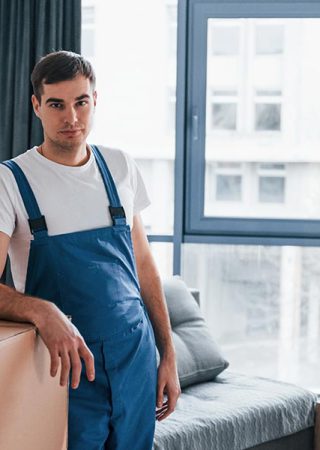 young-male-mover-in-blue-uniform-works-indoors-in-BU9HHGP